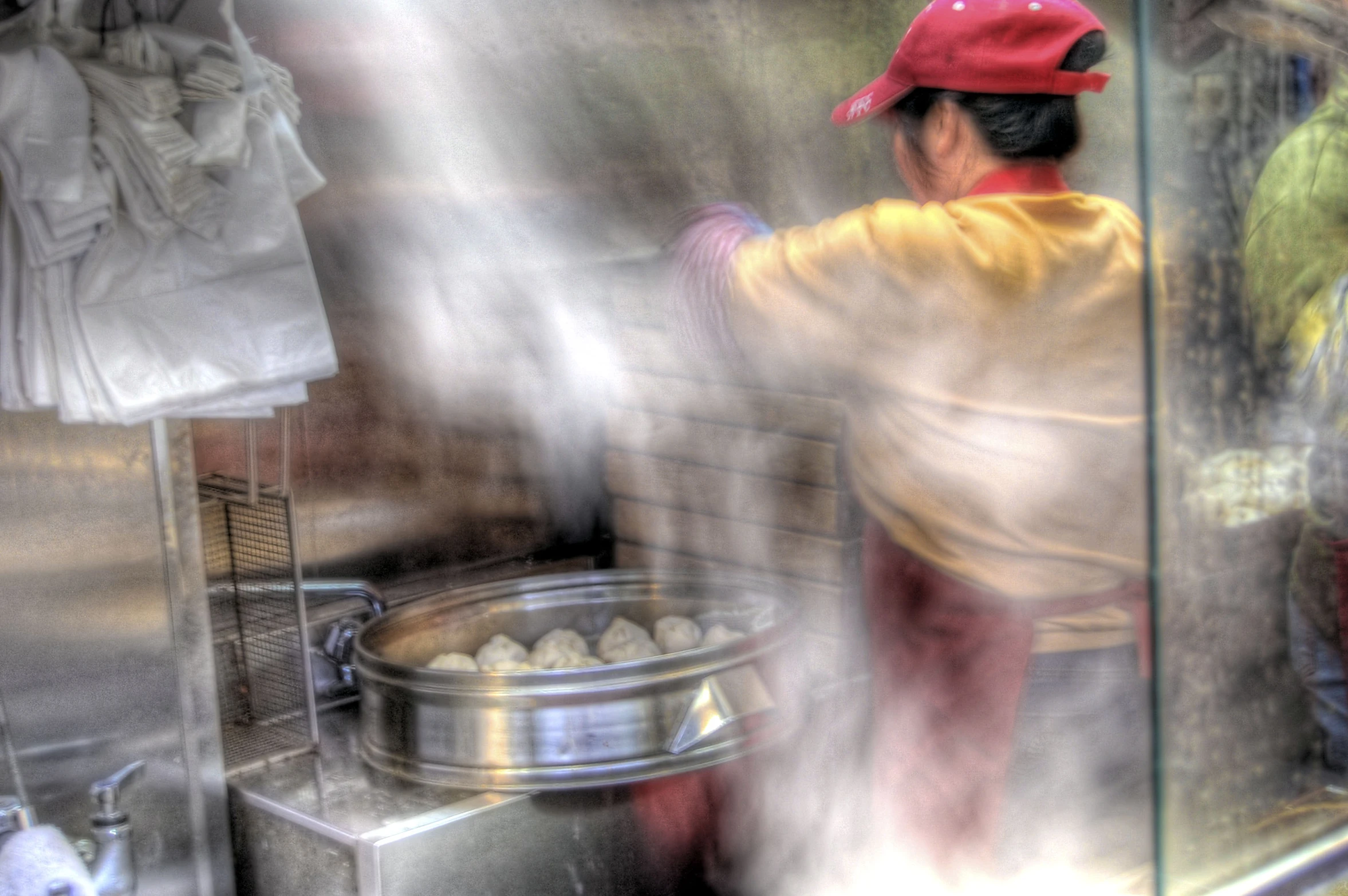 man cooking food outside in front of a glass case