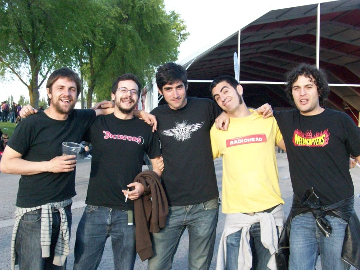 four young men posing for a pograph while holding their arms around each other