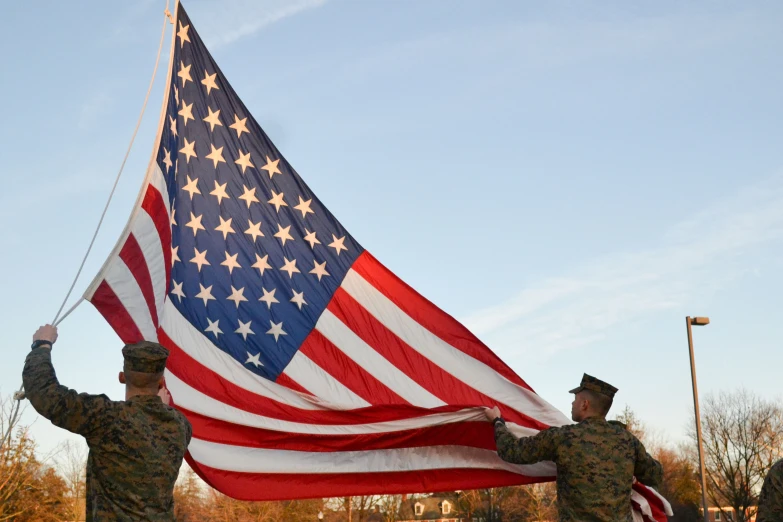 two soldiers holding a large flag under the blue sky