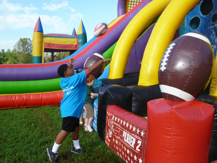 an inflatable football obstacle game with a boy with his hands on a bouncy ball