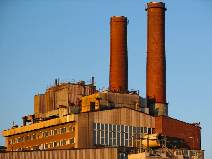 a factory with two smoke stacks that are yellow