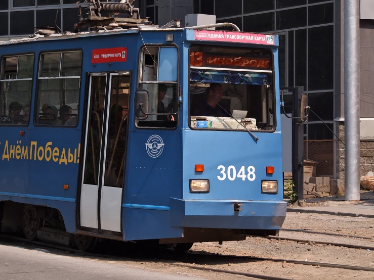 a blue tram with yellow lettering on the side