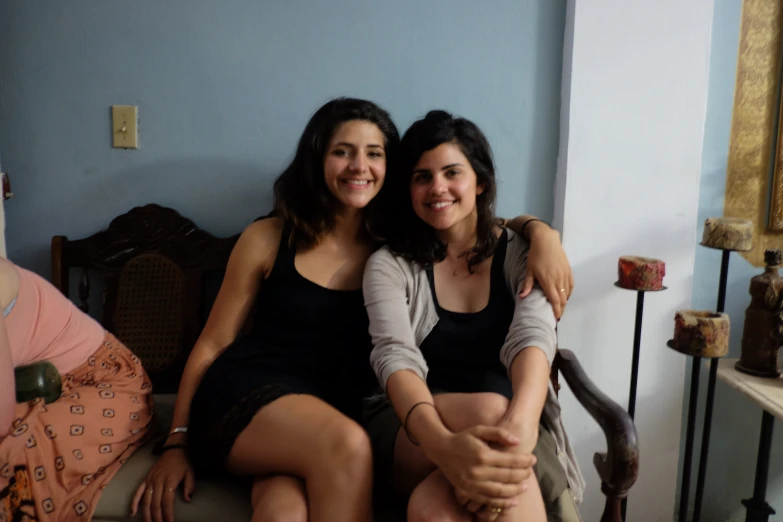 two women smile as they sit on a chair