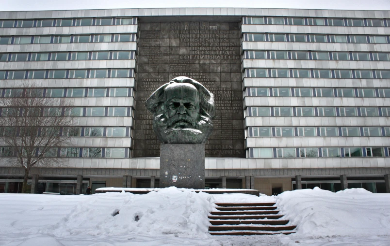 a stone head statue in front of the entrance to a building with many windows