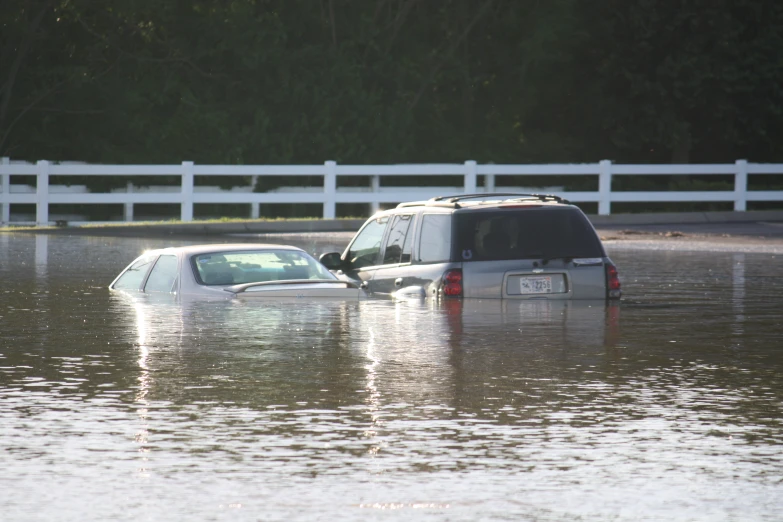 two vehicles that are driving in the flood waters