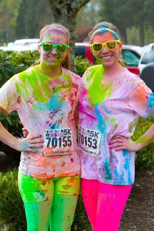 two women covered in multicolor paint posing for a po