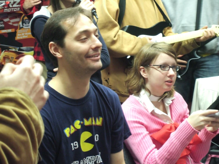 a man with a tooth brush in his hand looks to the side while people look on