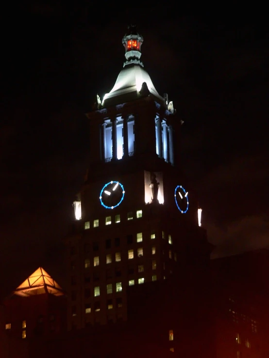 large lighted clocks decorate the top of a large building