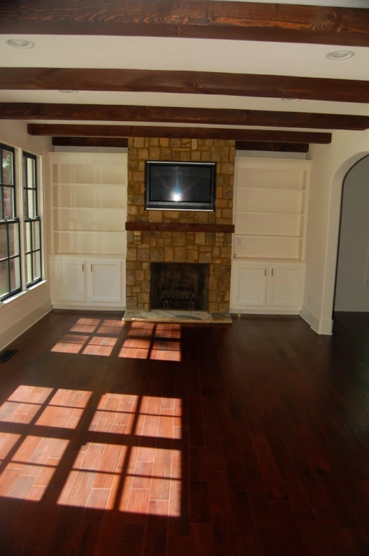 an empty living room with hardwood floors and a television in the fireplace