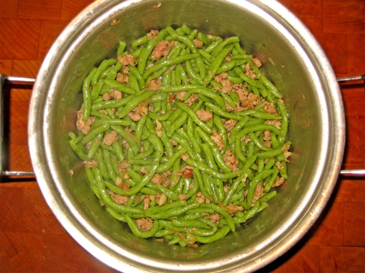 a bowl of green beans are on a wooden table