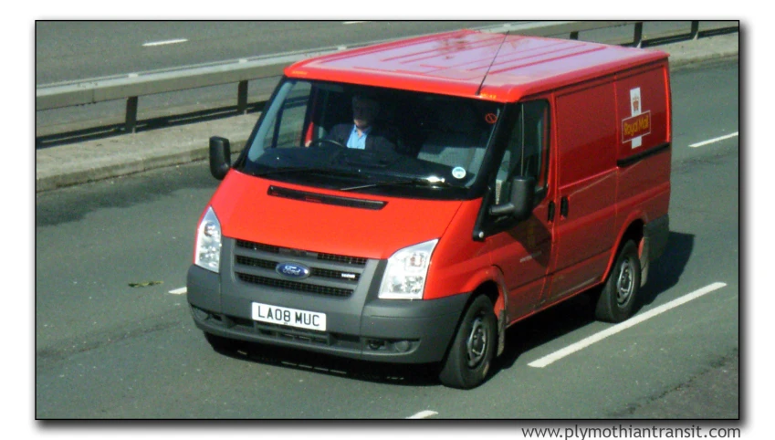 red van driving down an empty street on a sunny day