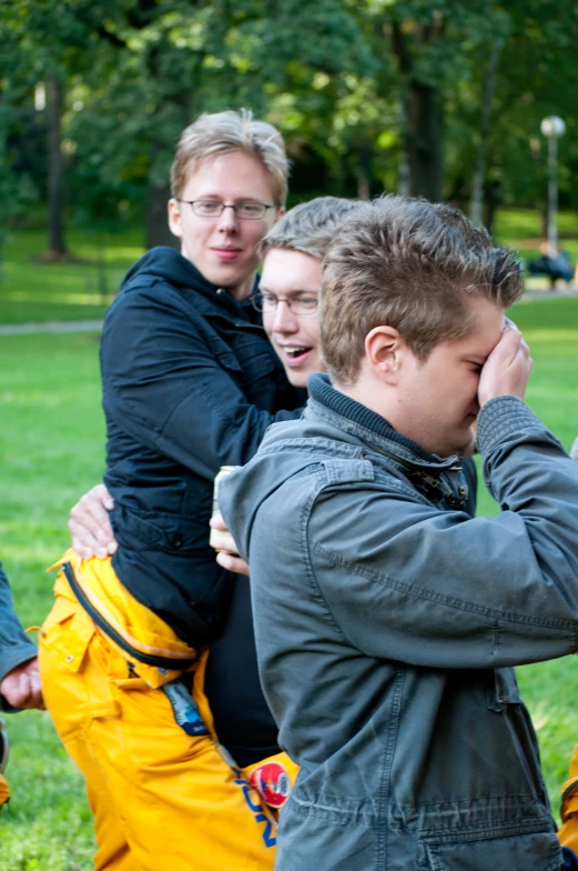 three people are huddled together in the park