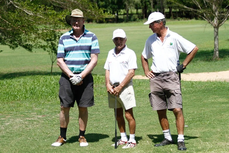 two men and one man standing in the grass with their golf club