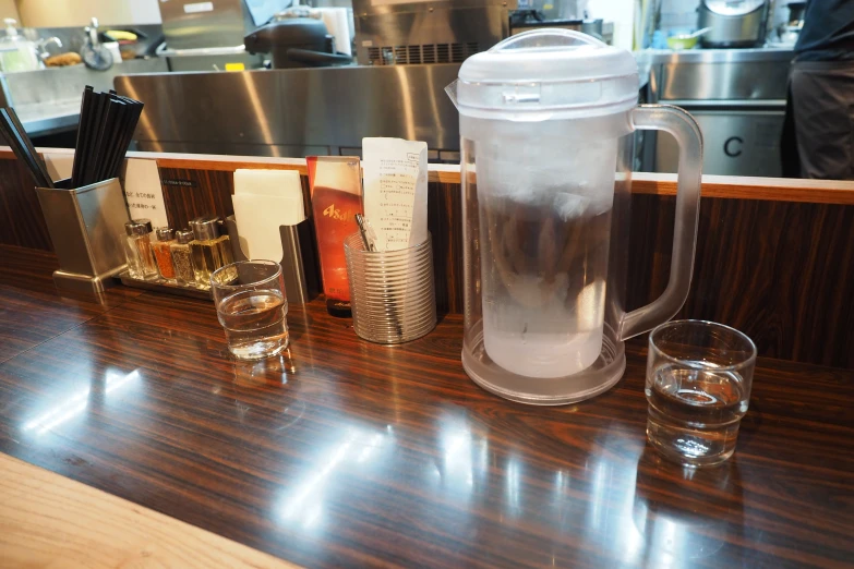 a counter topped with a blender and two glasses