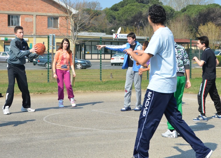 a group of people playing basketball on an asphalt court