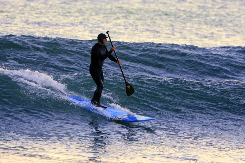 a man surfing in the ocean riding a paddleboard