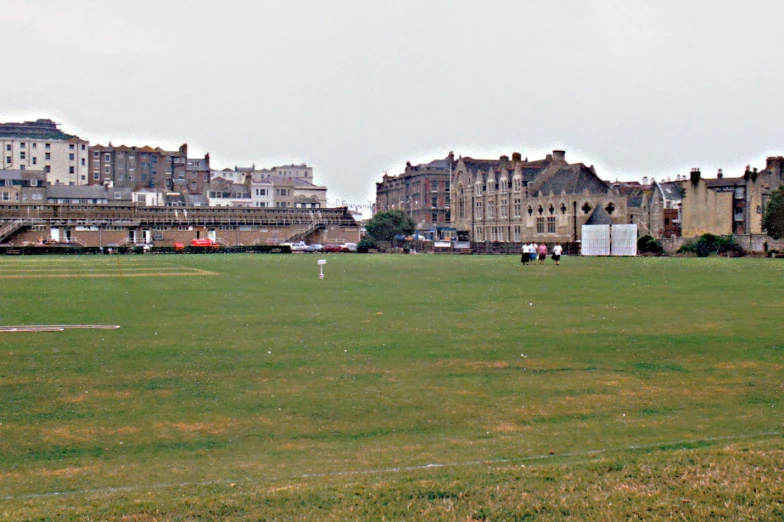 there is a large grassy field in front of some buildings