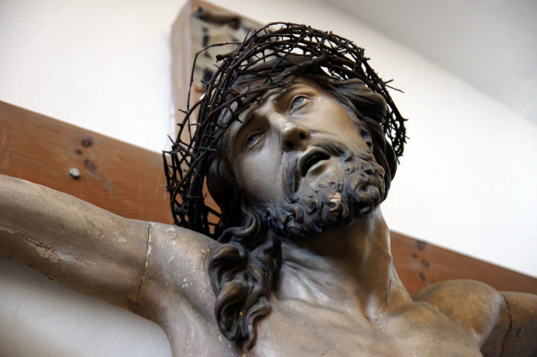 jesus with nails on his head and beard hanging from a cross