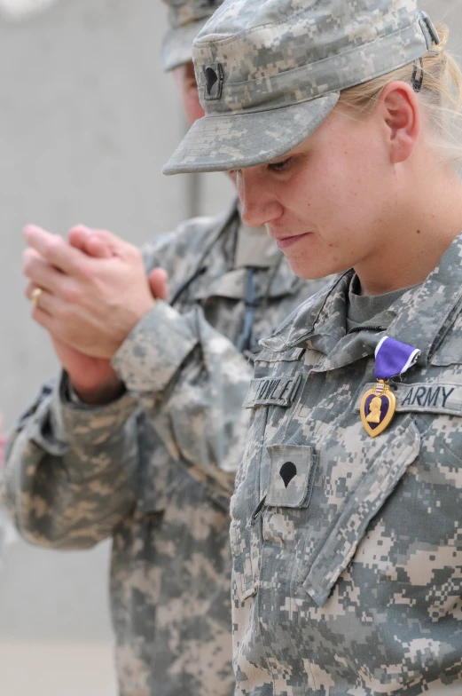 woman in uniform holding out her hands for another woman to put the medal on