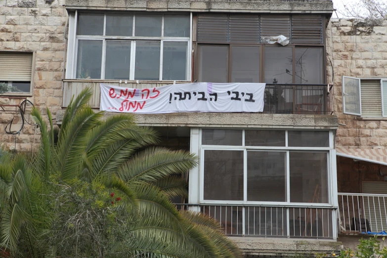 a banner on an apartment building with palm trees behind it