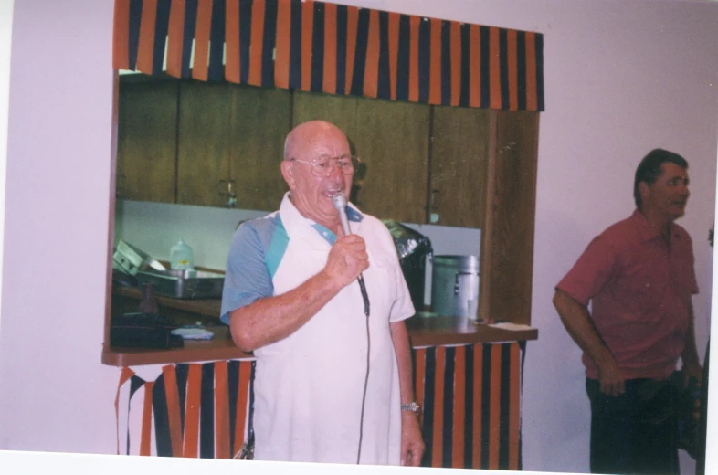 a man in a kitchen singing into a microphone