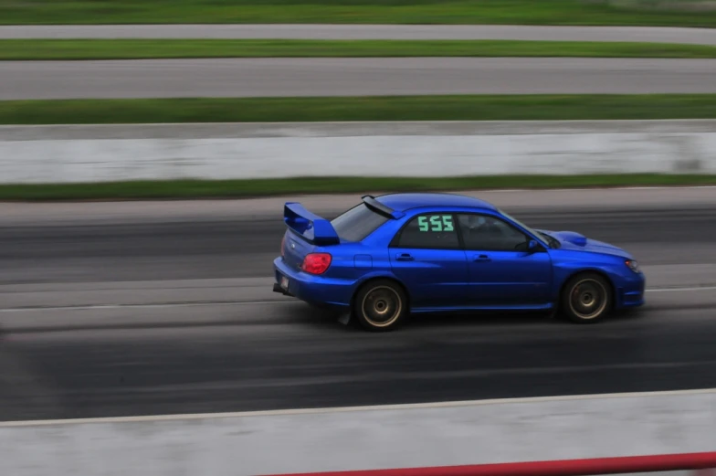 a small blue car driving down the track