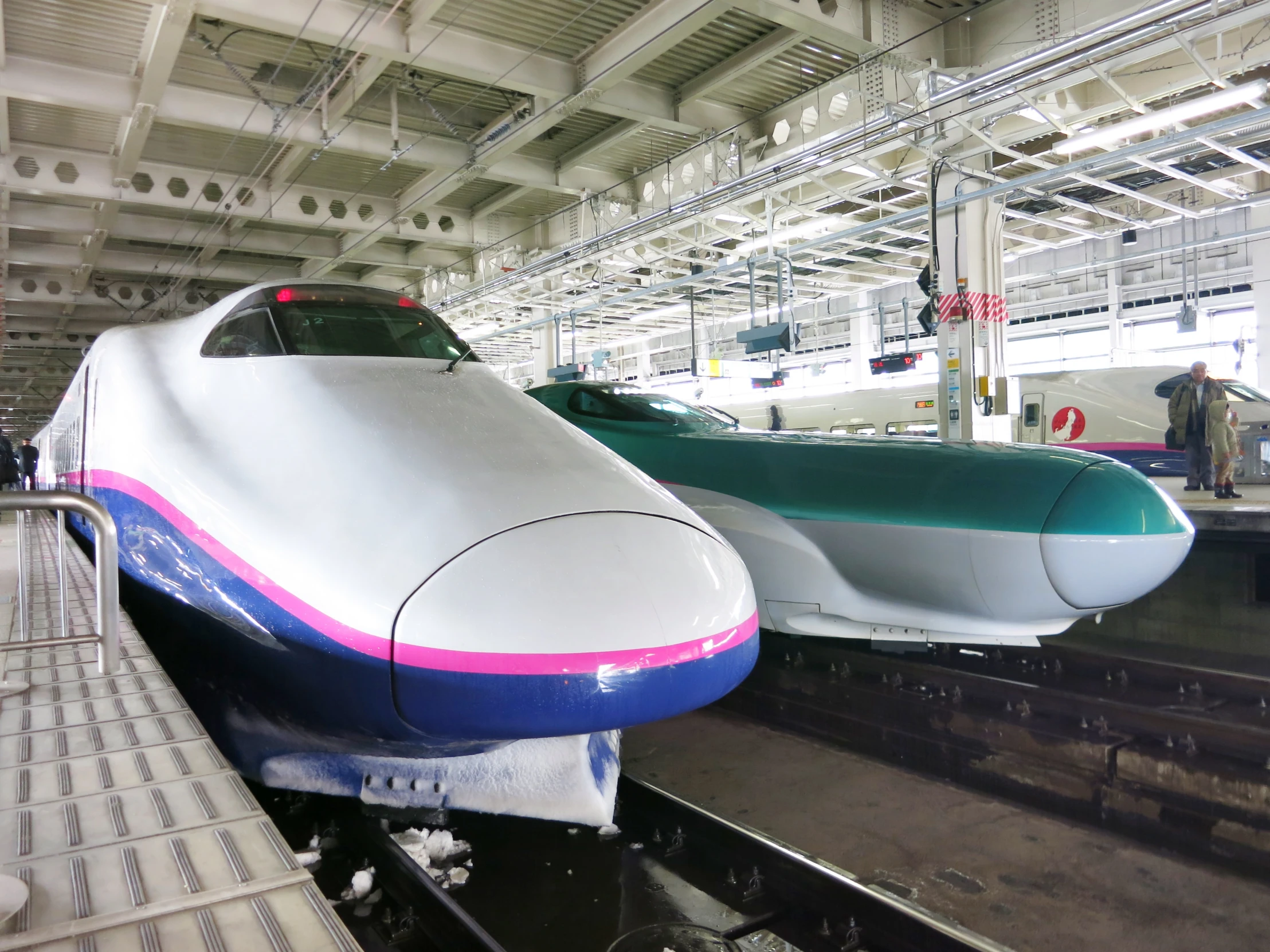 a white and blue train next to a man near other trains