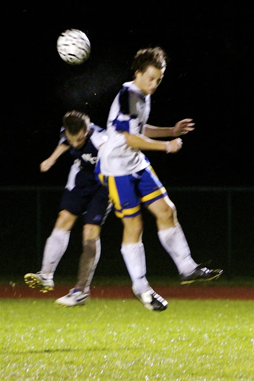 three young men playing soccer in the dark