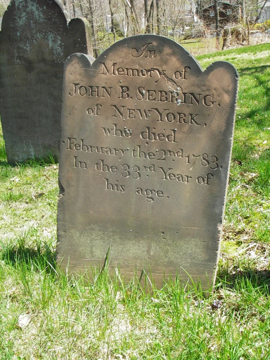 a headstone is sitting on the grass with a small cross in the background