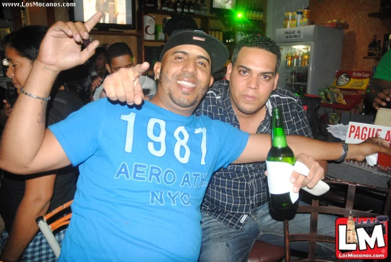 two men are posing at the bar with drinks