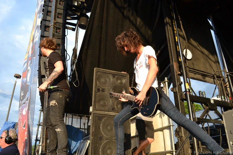 two people play guitars on stage as others look on