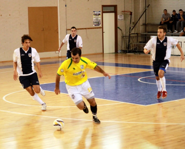 several men running in a gymnasium around a soccer ball