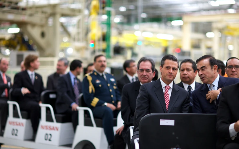 men in suits sitting together in a factory