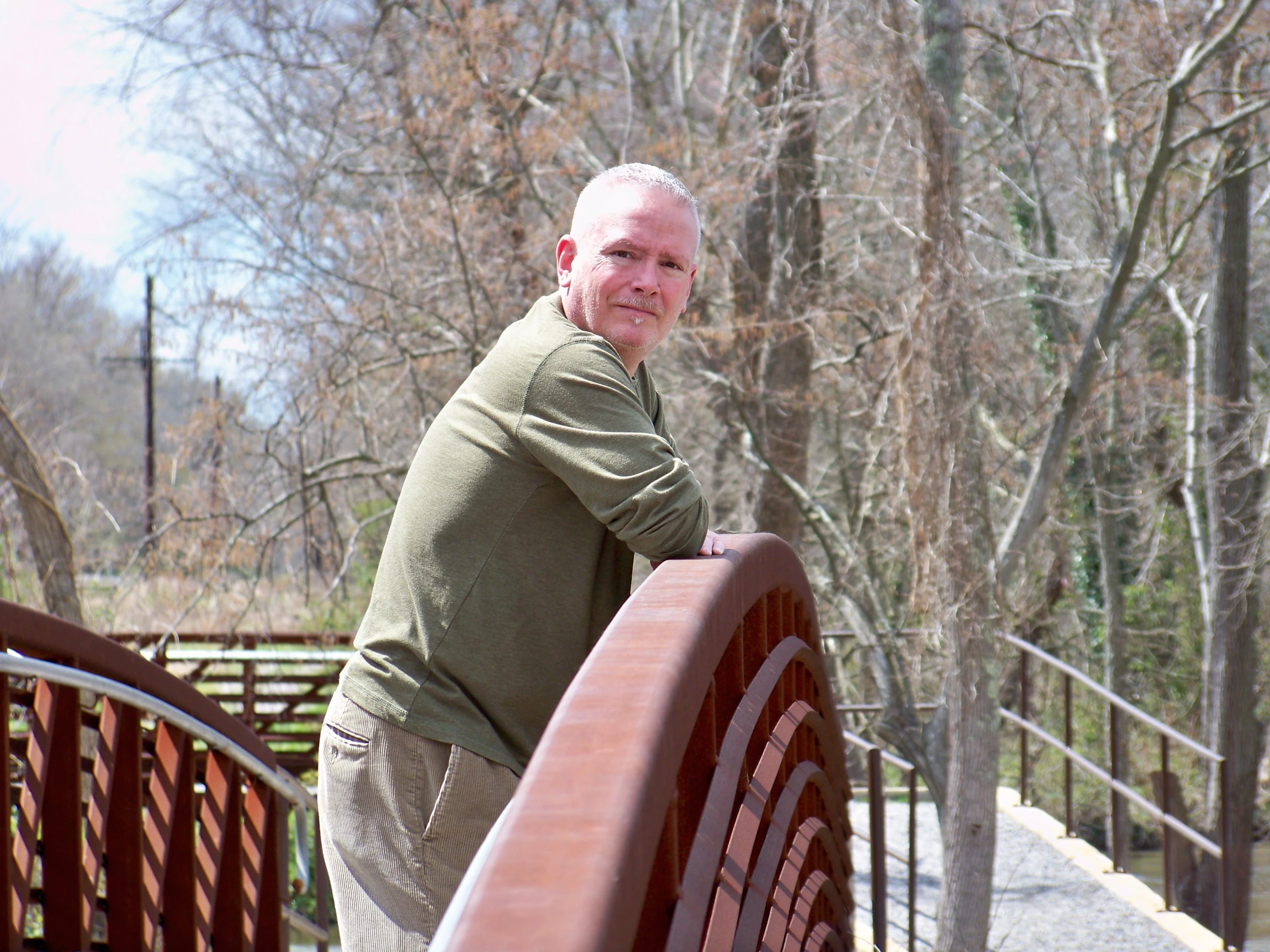 an old man leaning on a bench near the woods