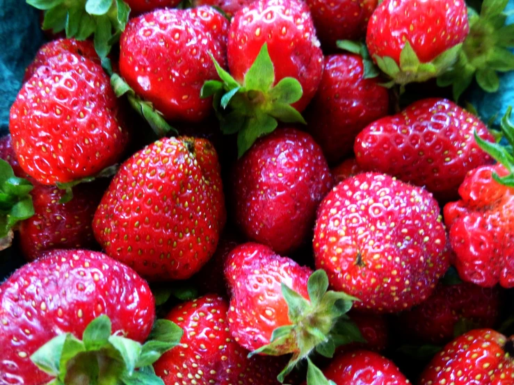 there are a group of strawberries with one large strawberry on the top