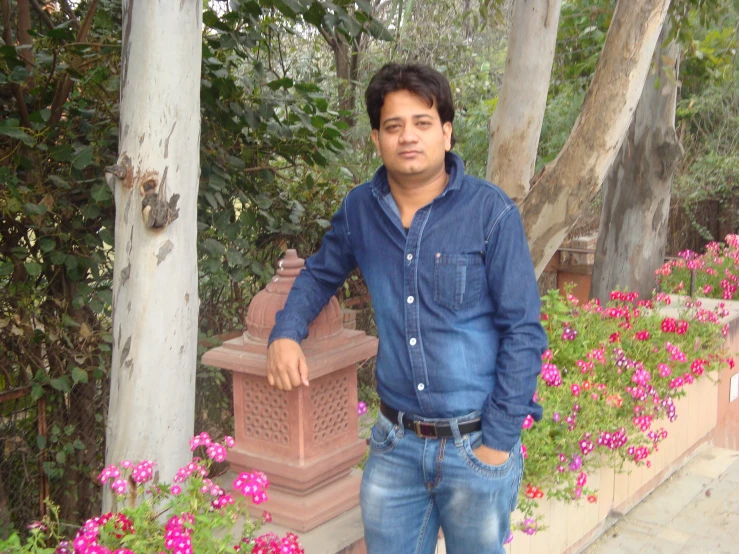 a man standing next to a pink flowered garden