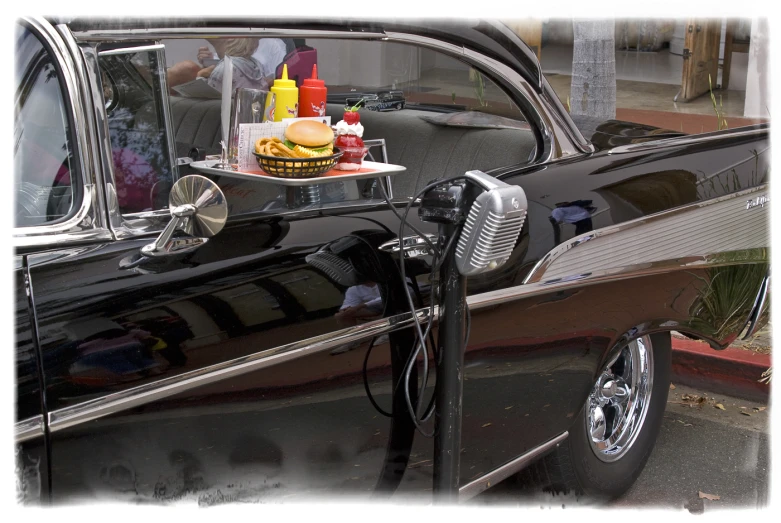 an old car with a tray of food on the tail gate