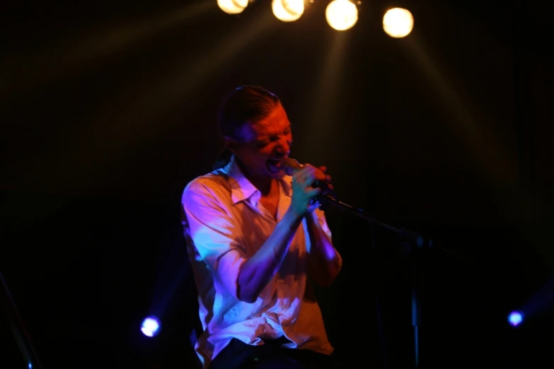 a man on stage with a microphone and bright lights