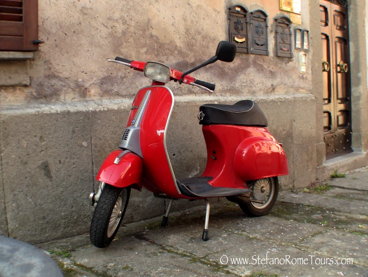 a red moped is parked on the street outside