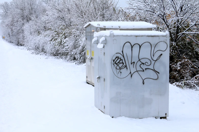 graffiti is all over this outhouse with some snow