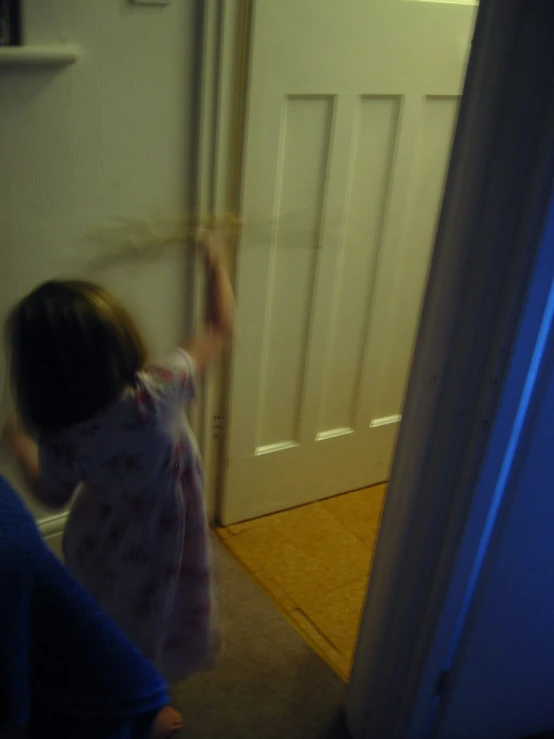 little girl reaching for door to open and another child standing nearby