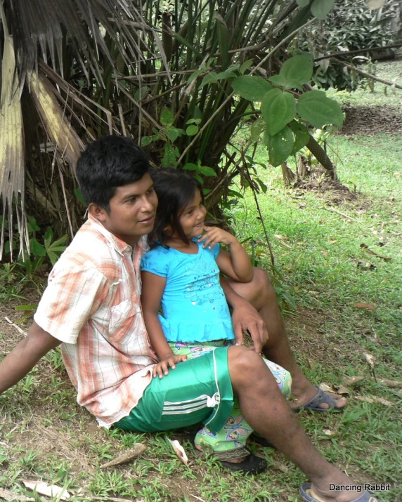 a man and a little girl sitting on the ground