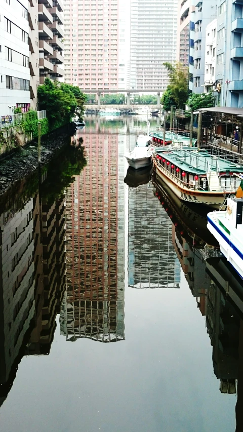 several boats docked along a waterway with a row of tall buildings in the distance