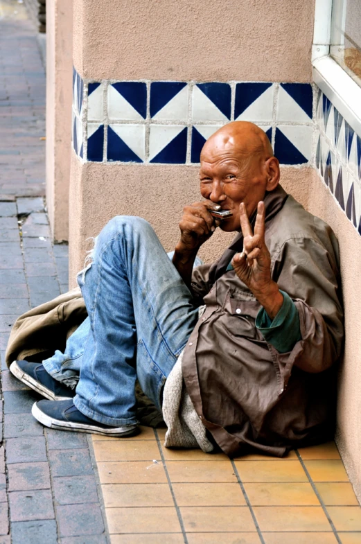 the man is sitting by the building smoking