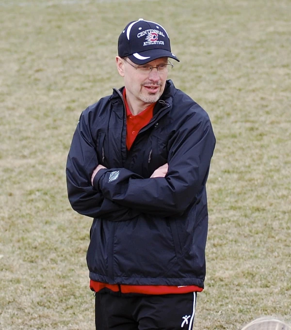 a man in black jacket and red and white shirt standing next to a frisbee