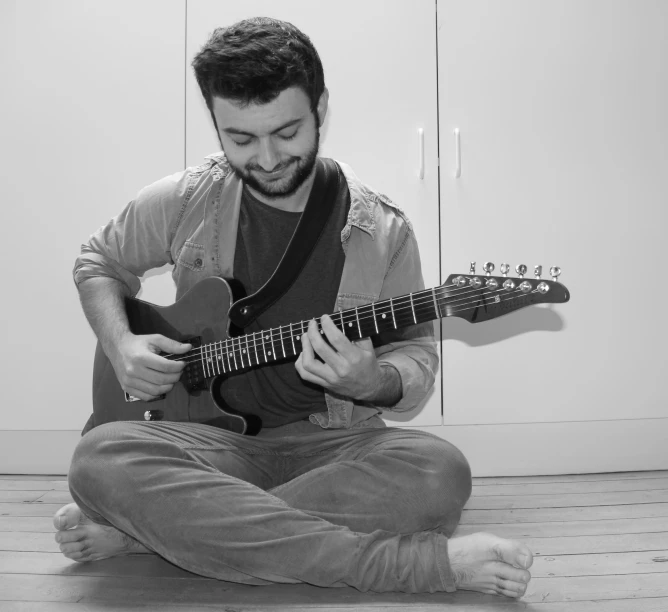 a man that is sitting down playing a guitar