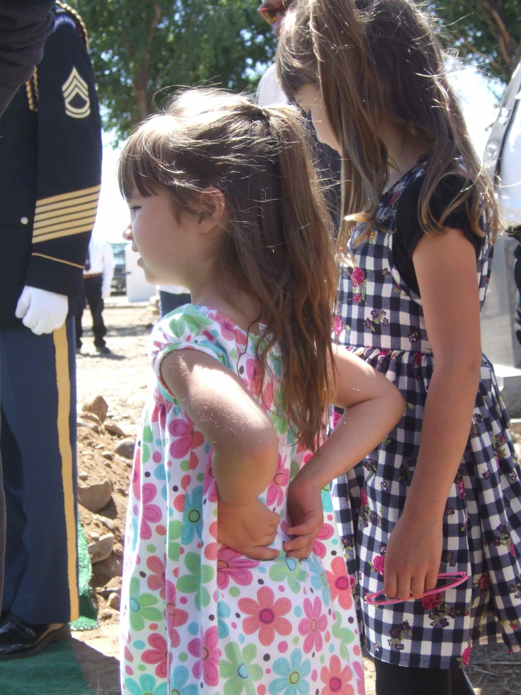 two little girls wearing dresses holding a teddy bear