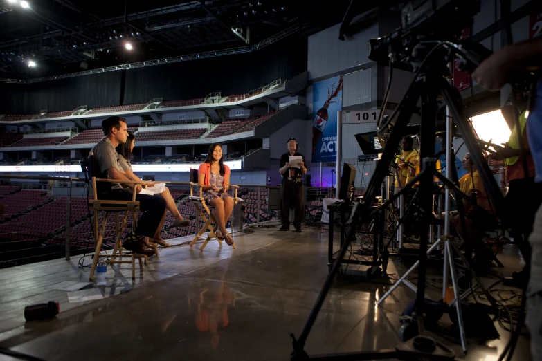 a group of people sit and talk in an empty, dark concert venue