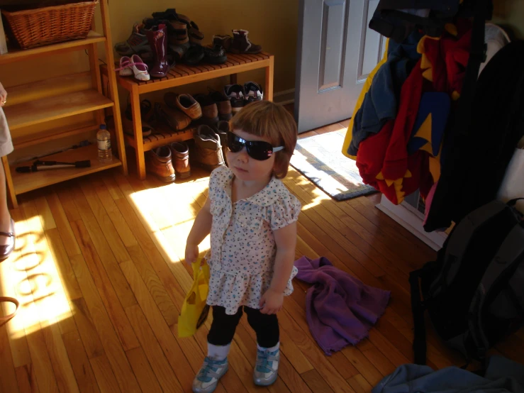 a little girl wearing sunglasses is standing by her closet
