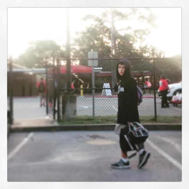 a man holding a handbag standing on a tennis court